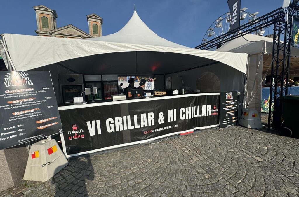 We Grill & You Chills uppställning med tält och serveringsdisk på ett event